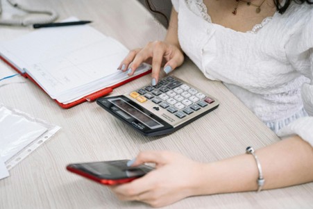 Women trying to calculate investment loan using her phone and calculator. 