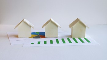 Wooden houses on spreadsheets showing investment properties.