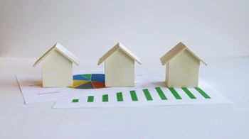 Wooden houses on spreadsheets showing investment properties.
