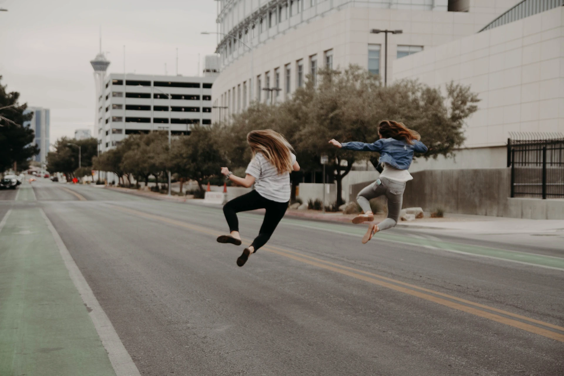 two woman jumping and clicking their heels in the middle of the road
