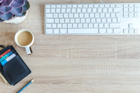 wallet with credit cards next to coffee cup and keyboard