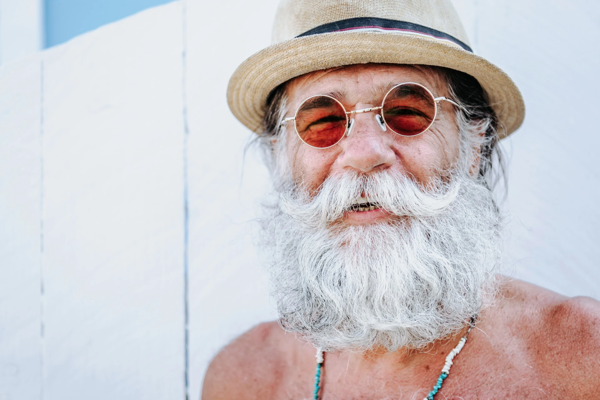 man with big bushy white beard and moustache wearing a sun hat and tinted glasses