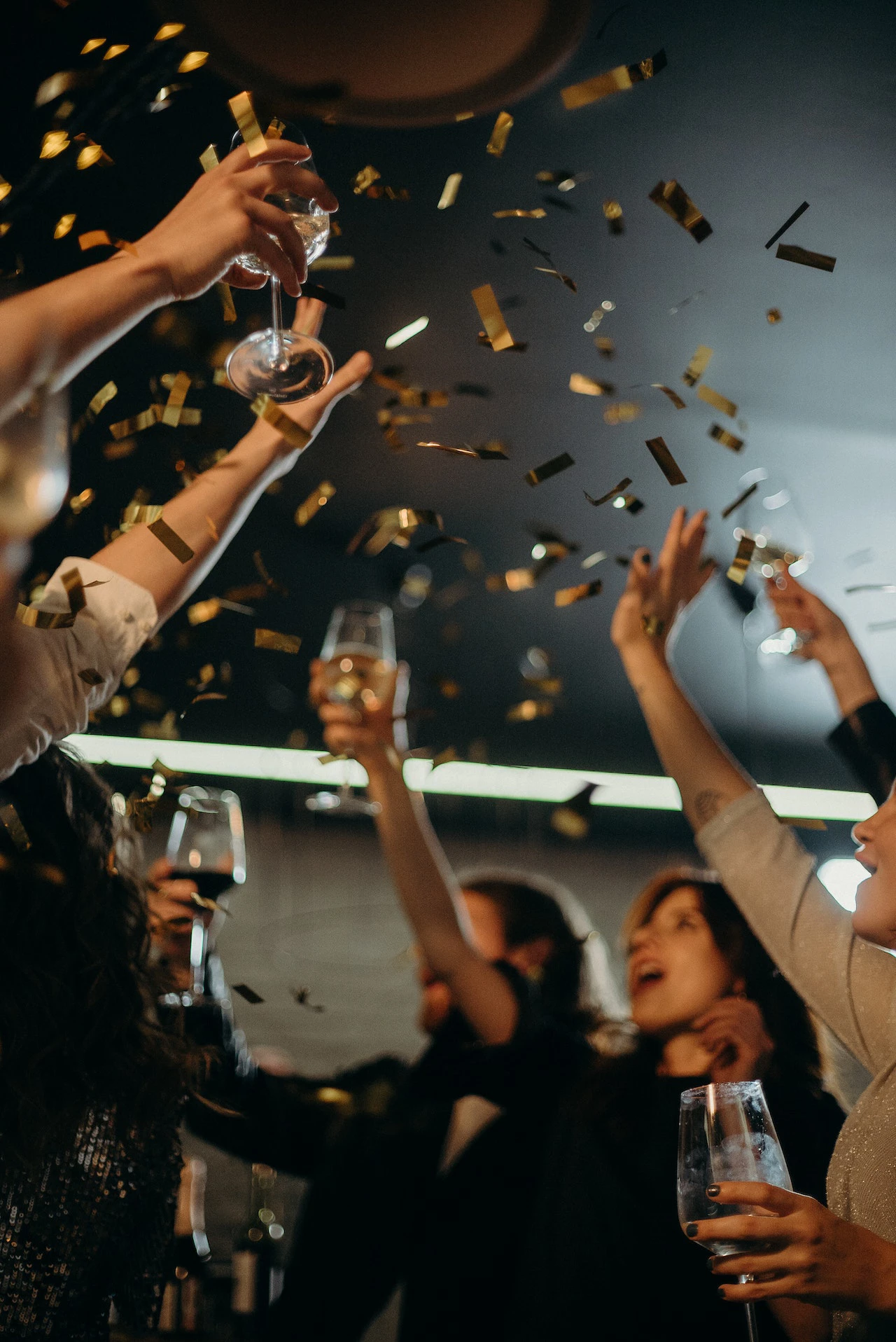 group of people with drinks celebrating while confetti rains down