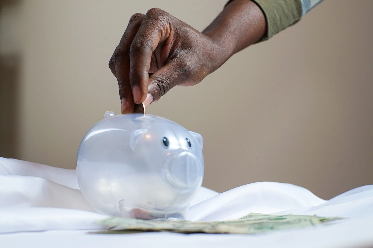 Person Putting Coin in a Piggy Bank - why use a broker